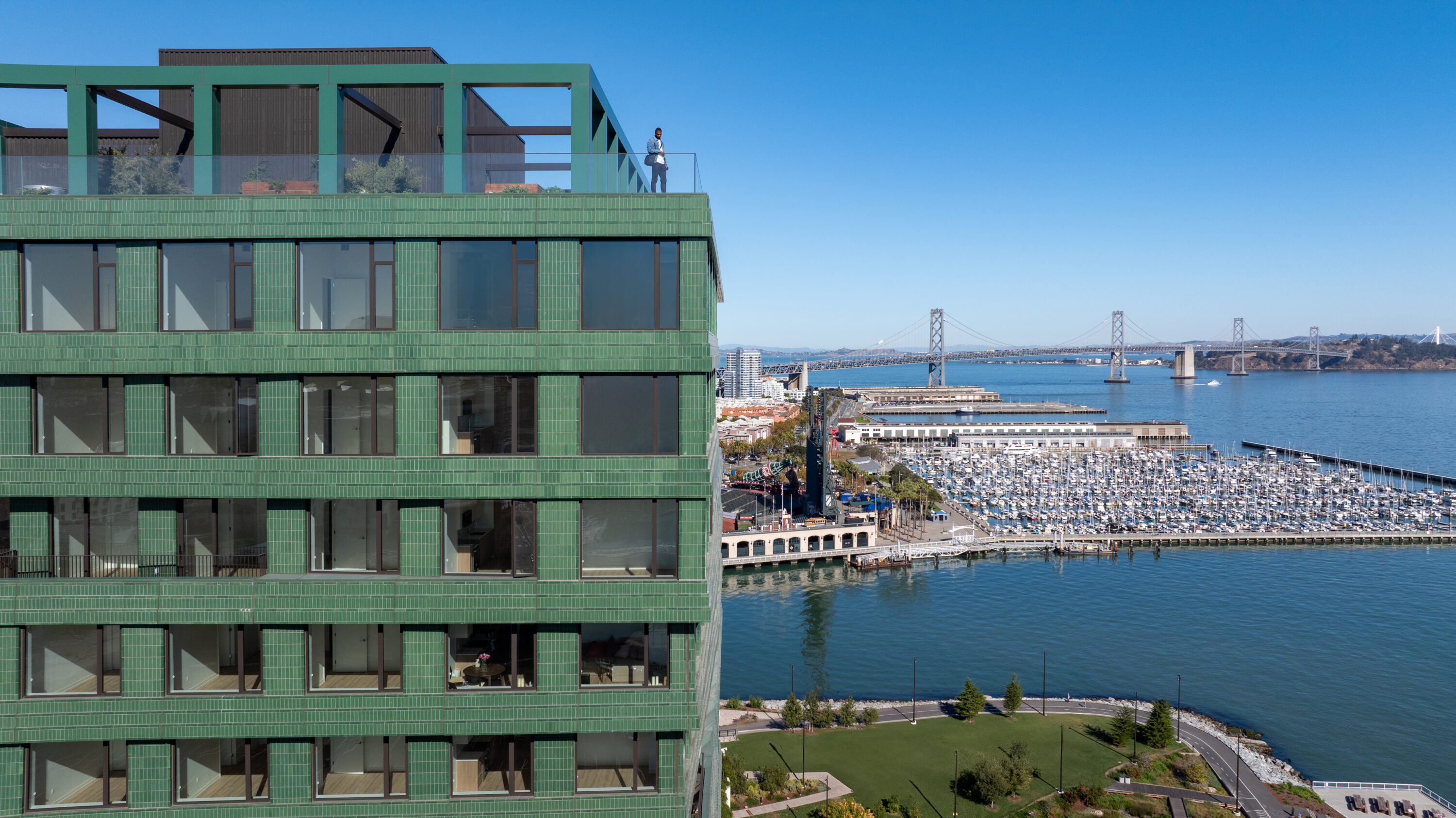 Green building overlooking bay waterfront with bridge view.
