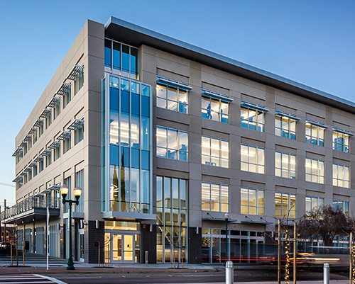 Modern office building with glass windows at sunset.